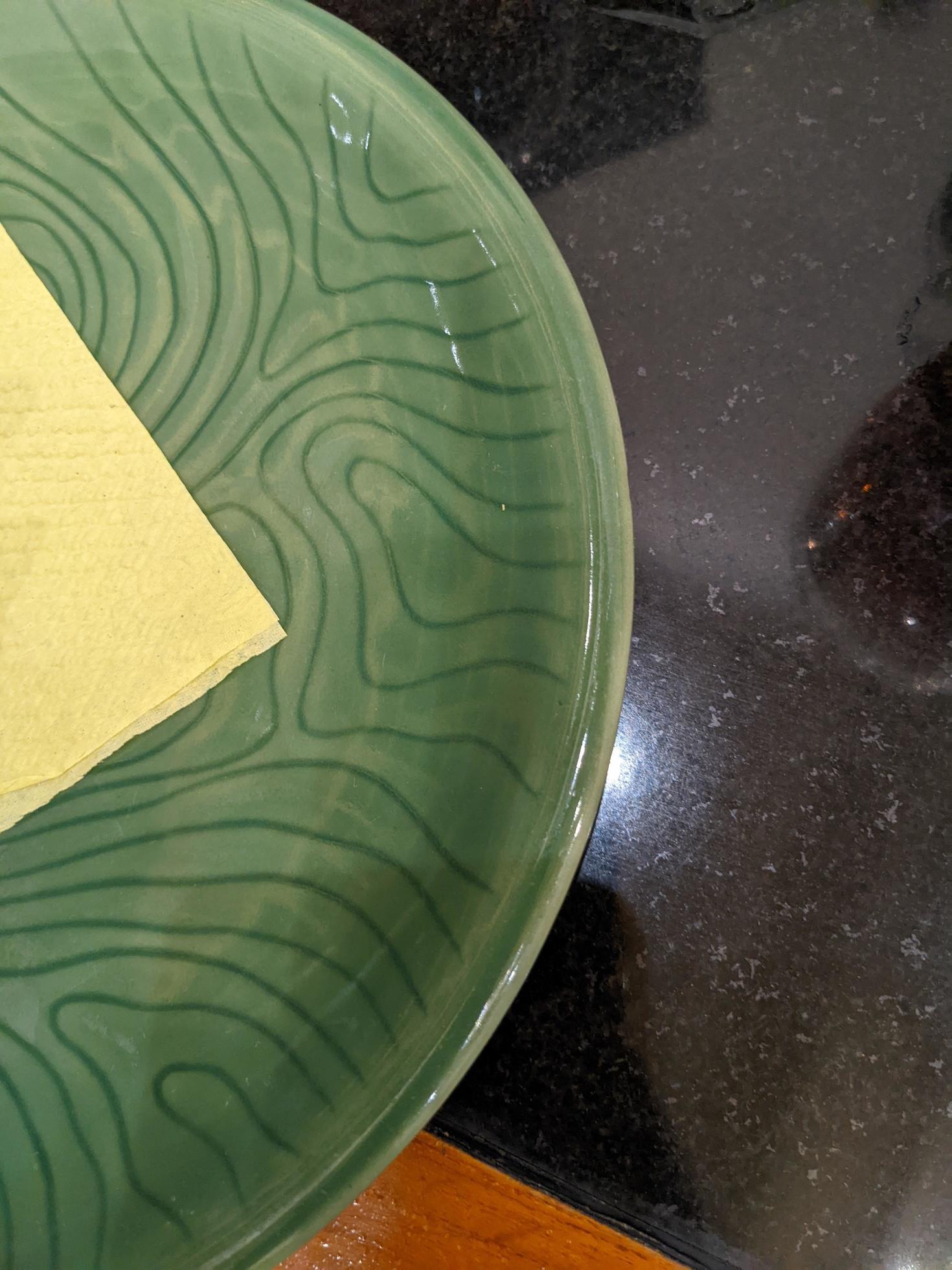 Empty green plate over the shiny table on the restaurant. The photo is suitable to use for restaurant background, menu poster and food content media. Stock Free