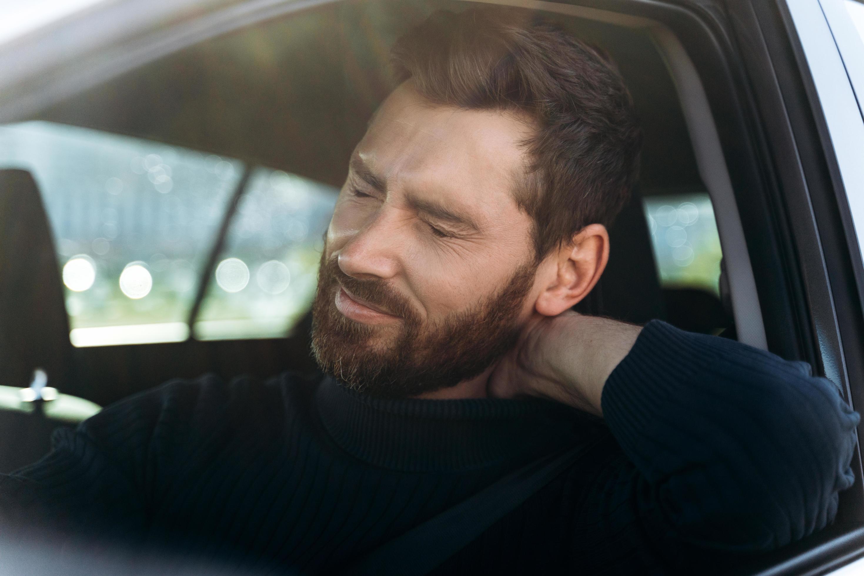 Tired businessman in car feeling strong neck pain and nerve inflammation, after long road. Transportation and health problems concept Stock Free