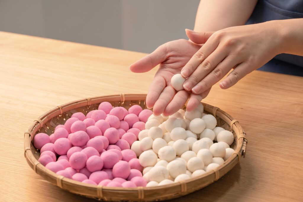 An Asia woman is making Tang yuan, yuan xiao, Chinese traditional food rice dumplings in red and white for lunar new year, winter festival, close up. Stock Free