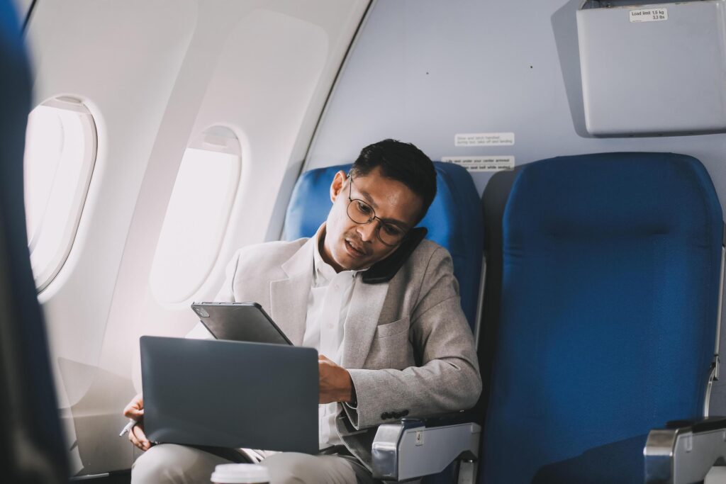 Airplane, travel and portrait of businessman working on laptop computer and smartphone while sitting in airplane. Stock Free