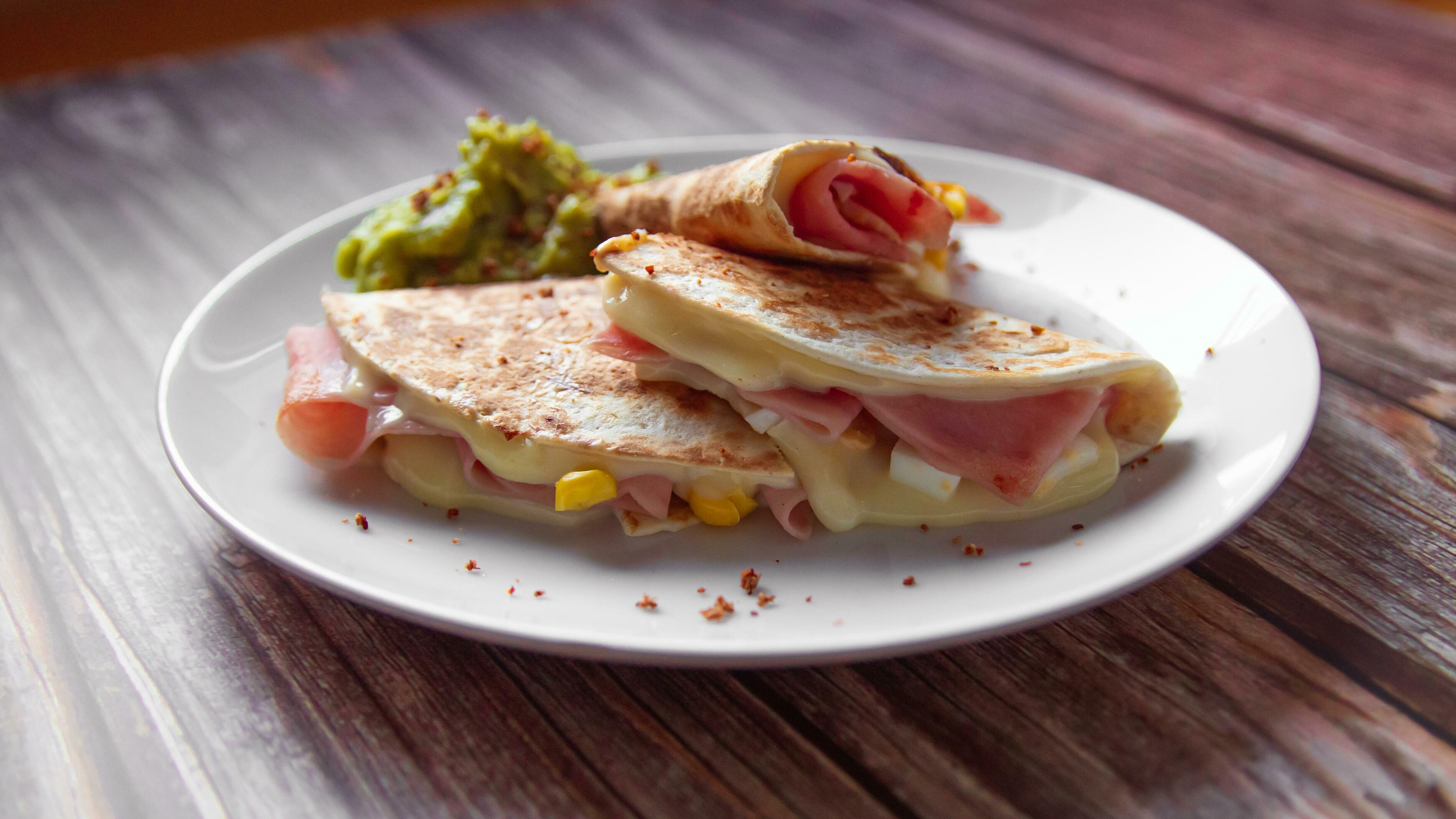 A plate of food with a quesadilla and guacamole on it. Stock Free