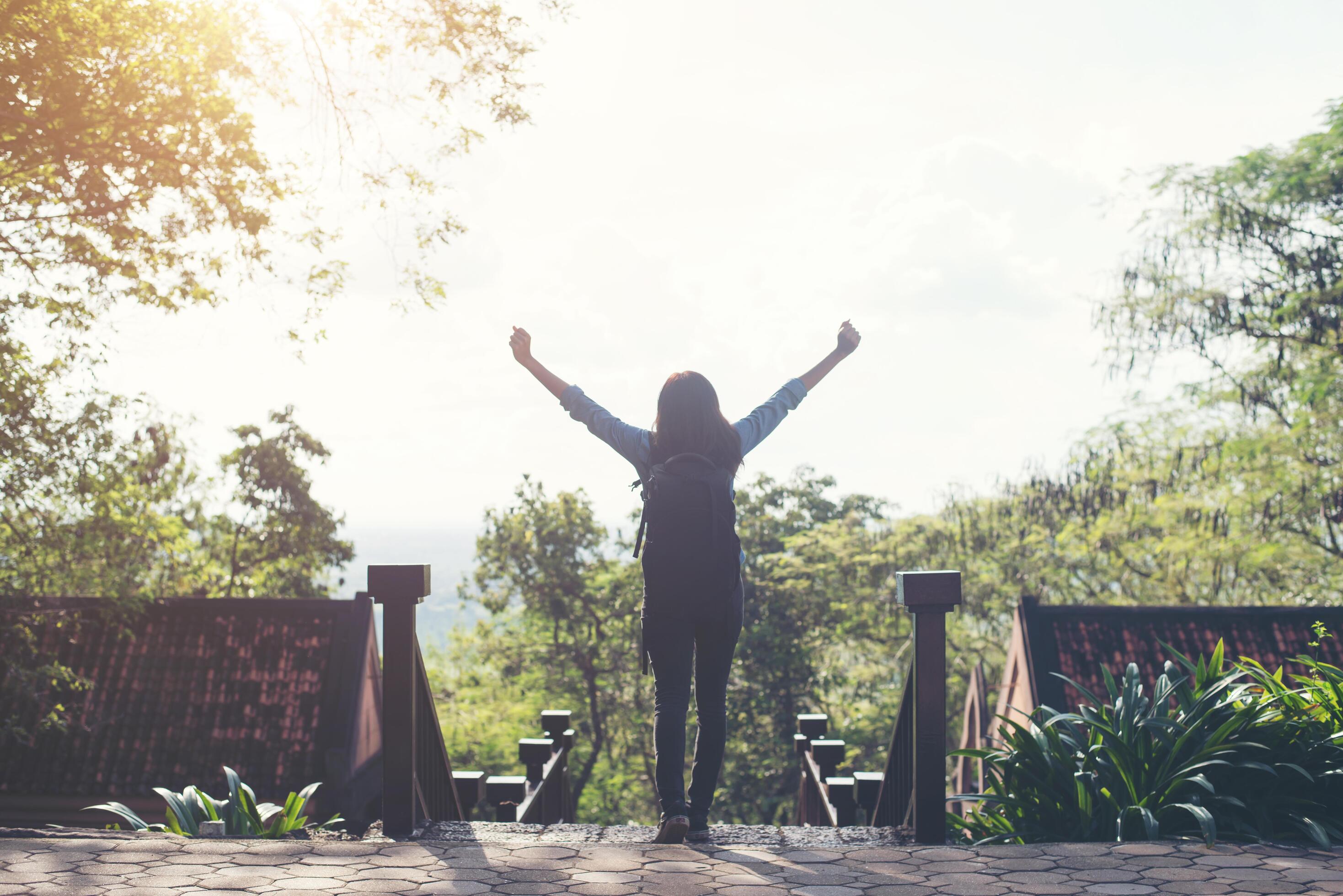 Freedom traveler hipster woman standing with raised arms and enjoying a beautiful nature. Achieved with adventure. Stock Free