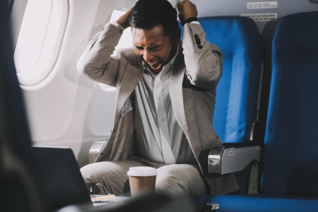 Stressed and professional Asian businessman in a business class, having a serious phone call with someone during the flight to a business meeting. Stock Free