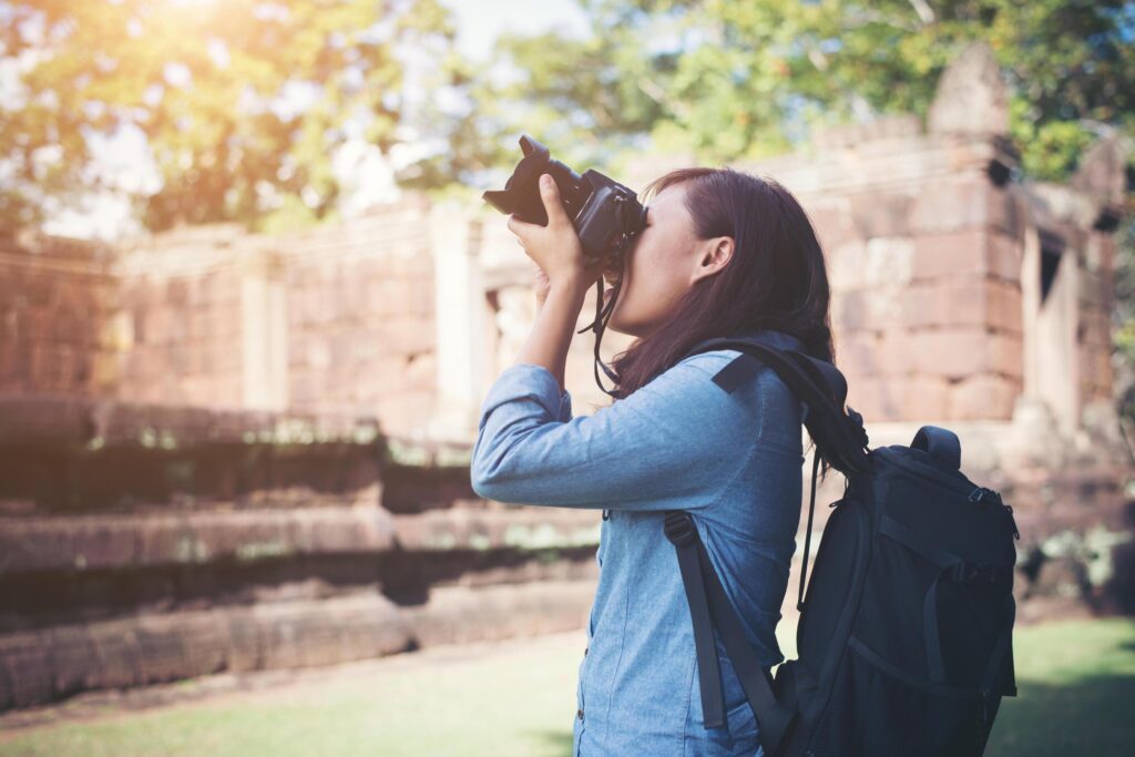 Young attractive woman photographer tourist with backpack coming to shoot photo at ancient phanom rung temple in thailand. Stock Free