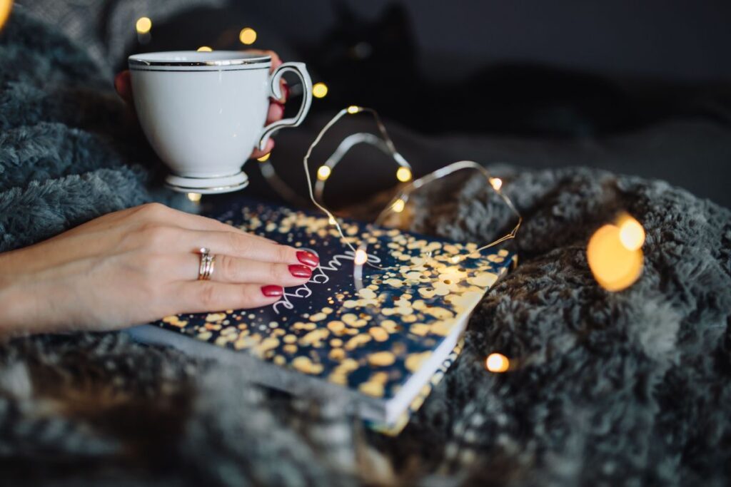 Young woman at home reading Hygge book and drinking Stock Free