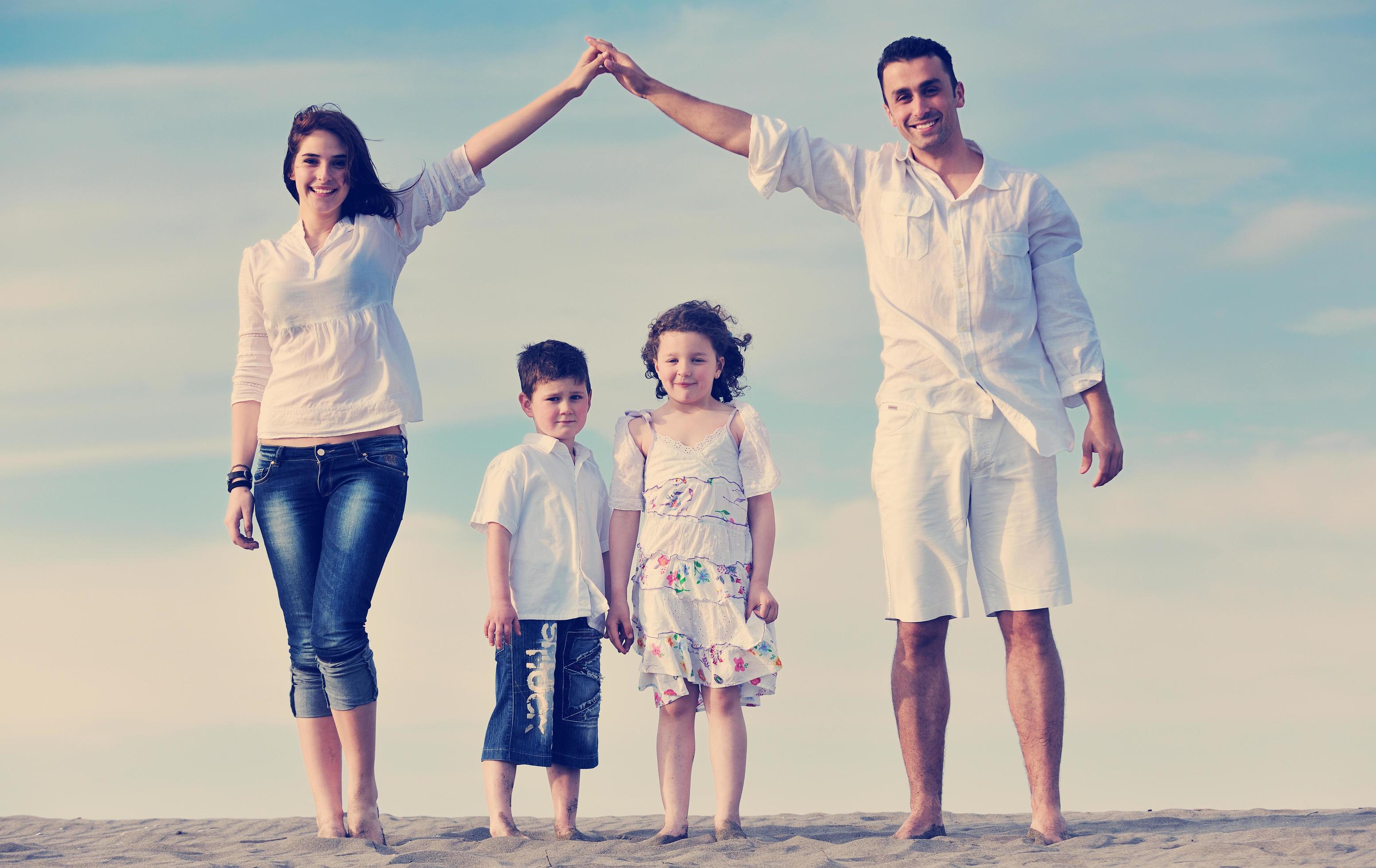 family on beach showing home sign Stock Free