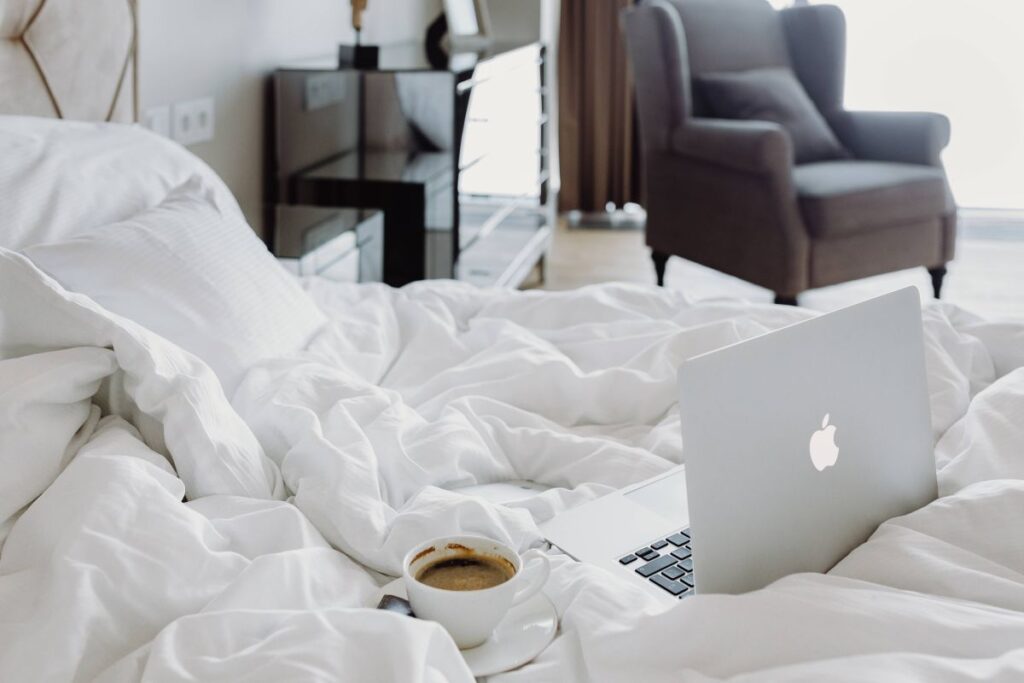 Woman working on a laptop while enjoying a breakfast coffee and chocolate in bed Stock Free