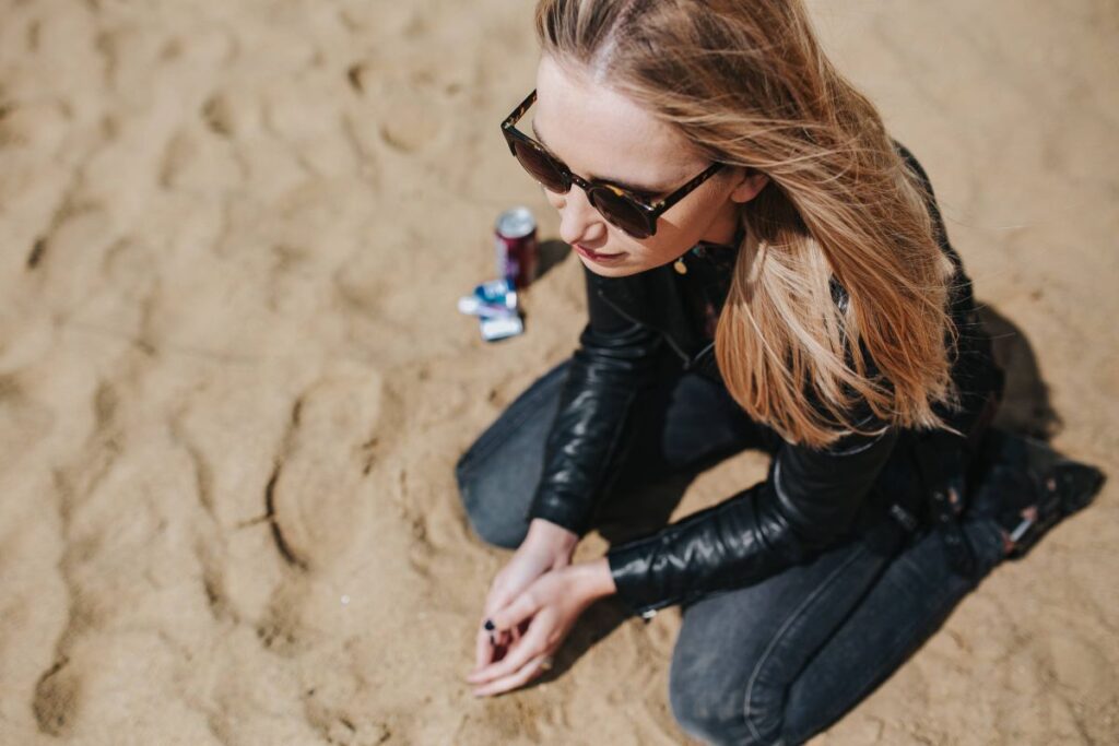 Young woman wearing a leather jacket and sunglasses on the beach Stock Free