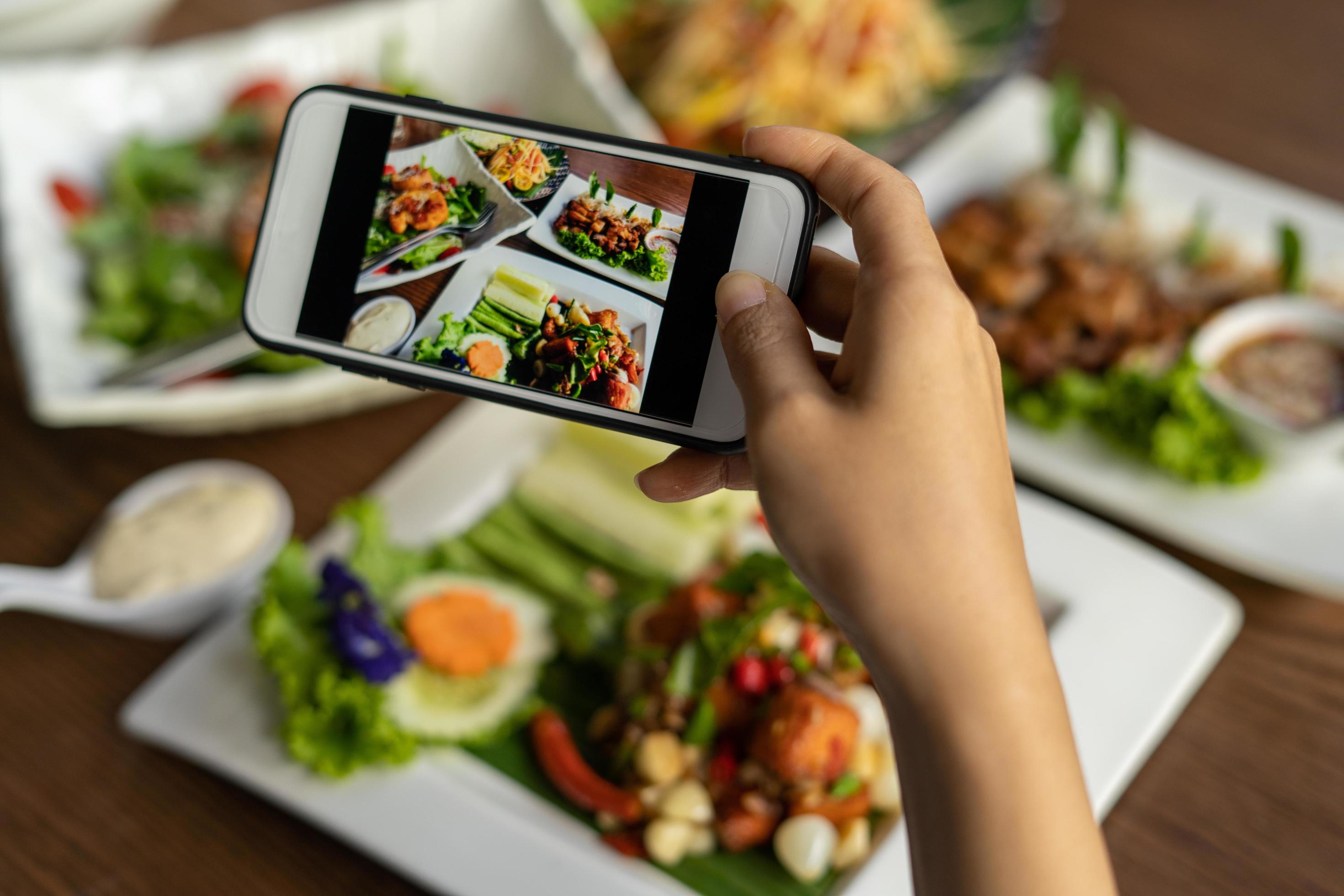 Woman take picture of a meal on the table after ordering food online to eat at home. Photography and use phone concepts Stock Free