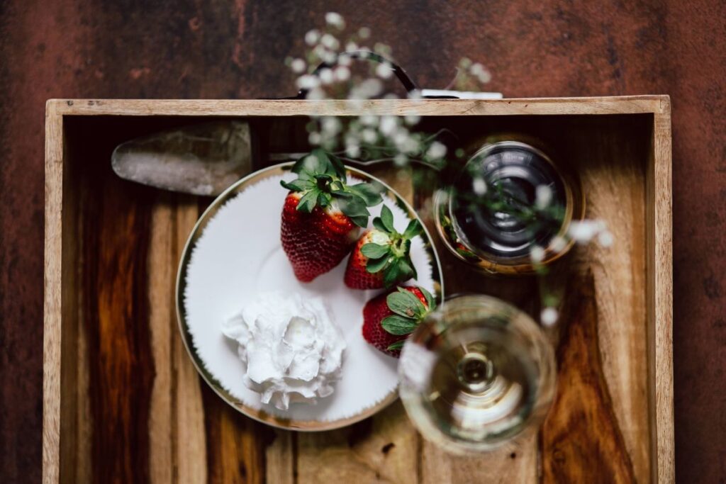 Strawberries with cream and glass of white wine on wooden tray Stock Free