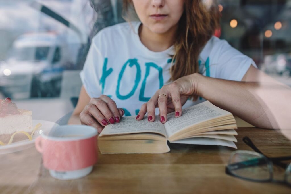 Woman reading book at coffee shop Stock Free