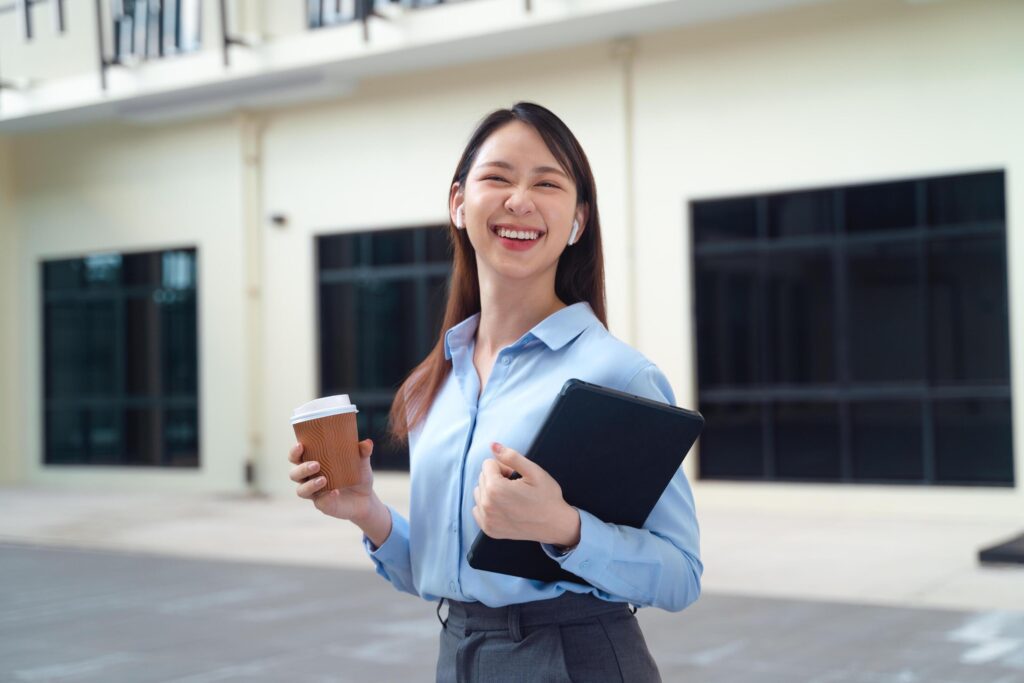 A business woman wearing a blue shirt and holding a cup of coffee and a tablet Stock Free