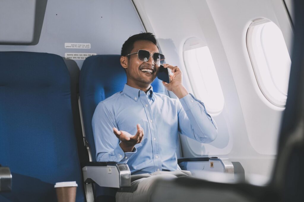 Traveling and technology. happy young businessman working on laptop computer and smartphone while sitting in airplane. Stock Free