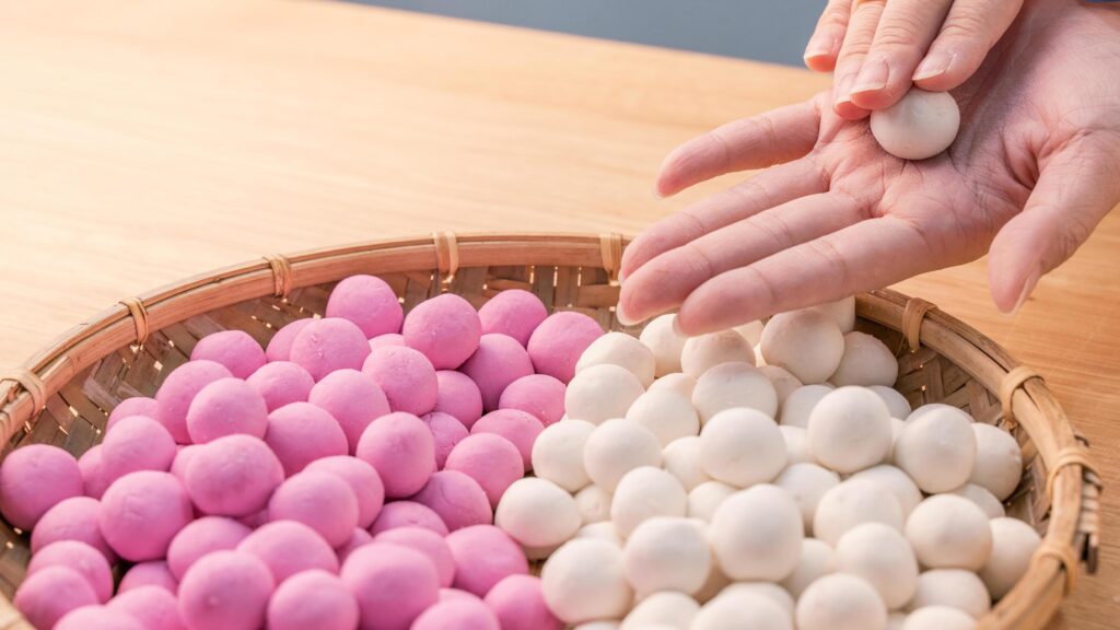 An Asia woman is making Tang yuan, yuan xiao, Chinese traditional food rice dumplings in red and white for lunar new year, winter festival, close up. Stock Free