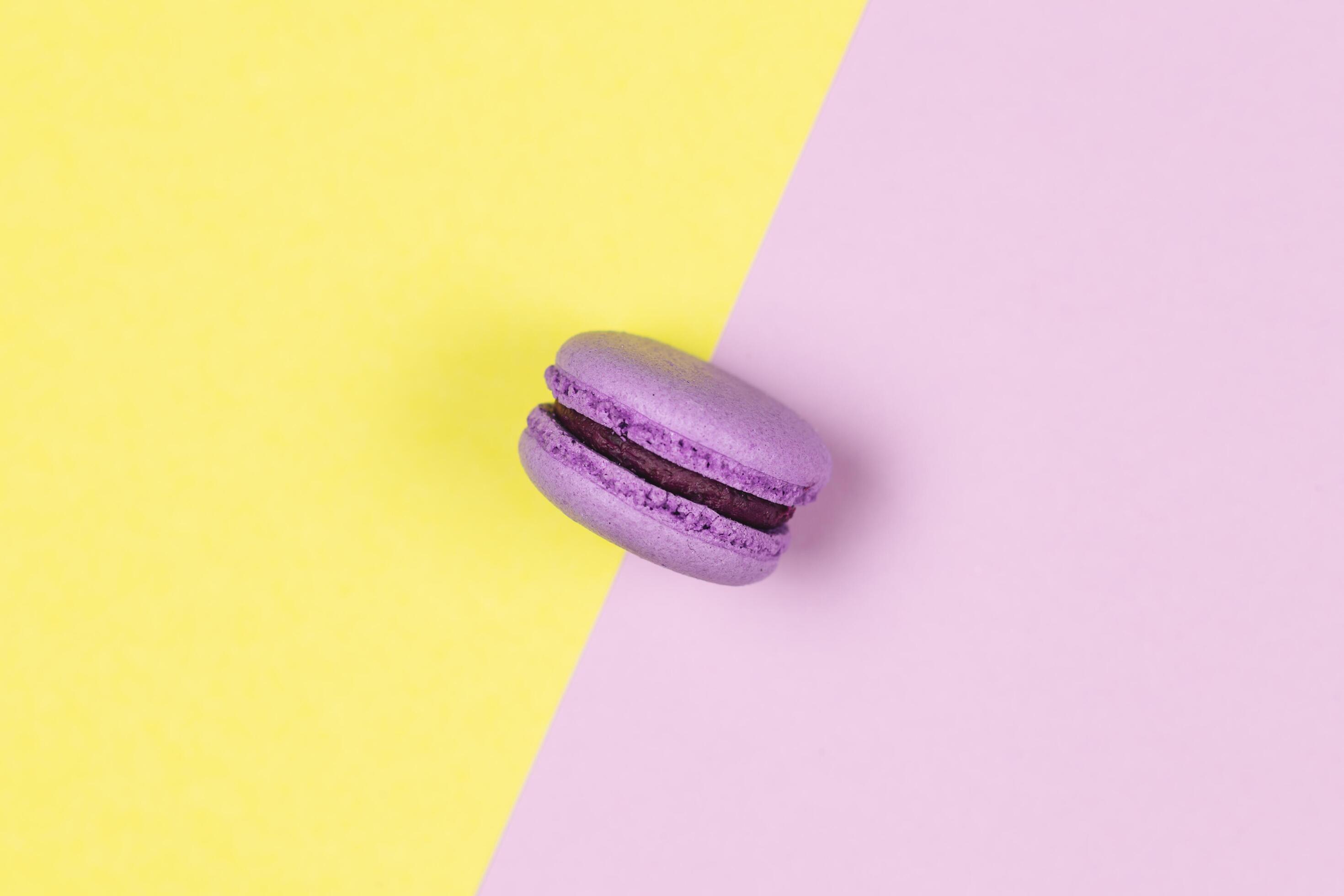 Purple french macaron on a yellow and purple background. Stock Free