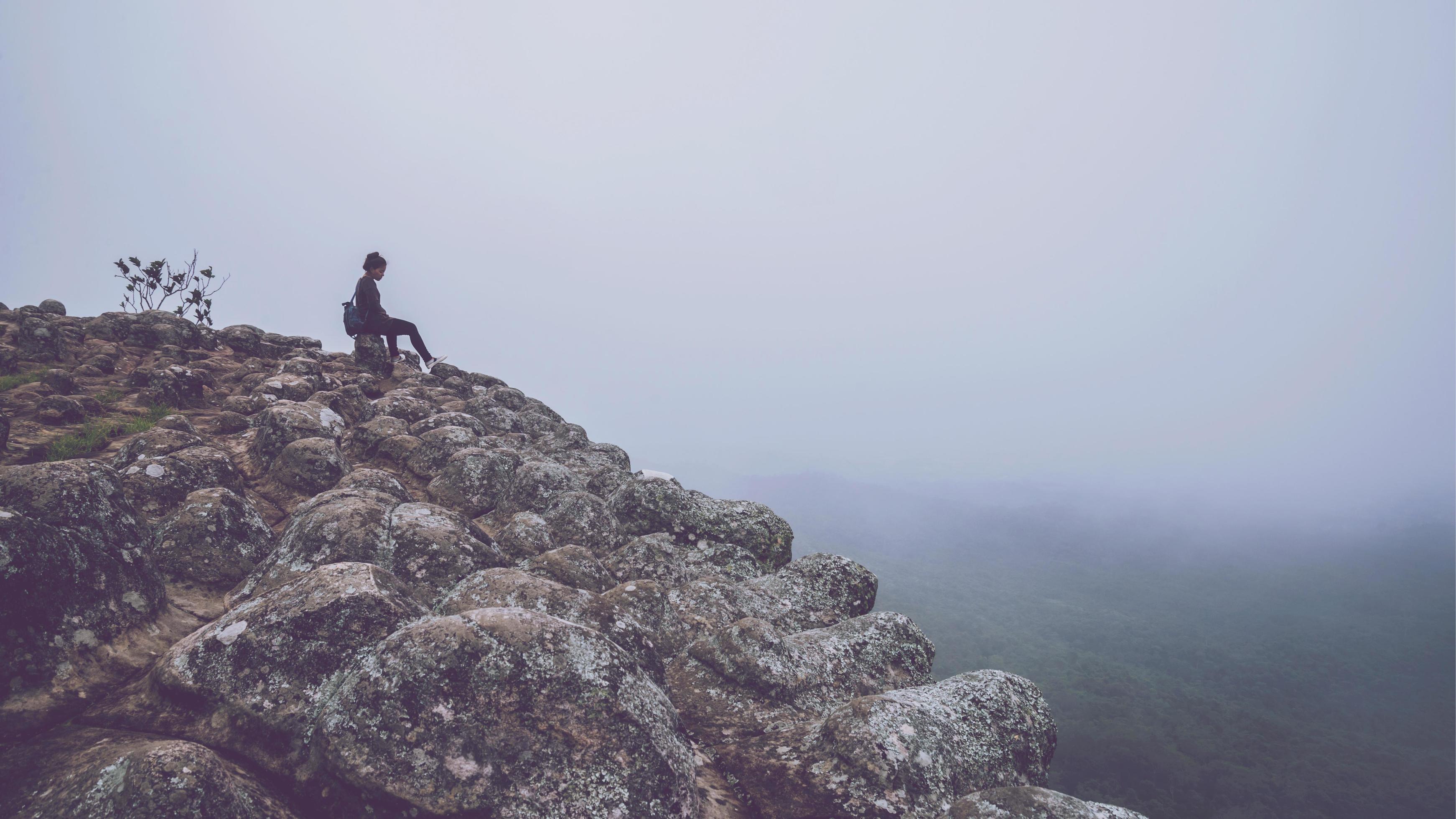 Asian women travel relax in the holiday. Sitting on a rocky mountain cliff. Wild nature wood on the mountain. Stock Free