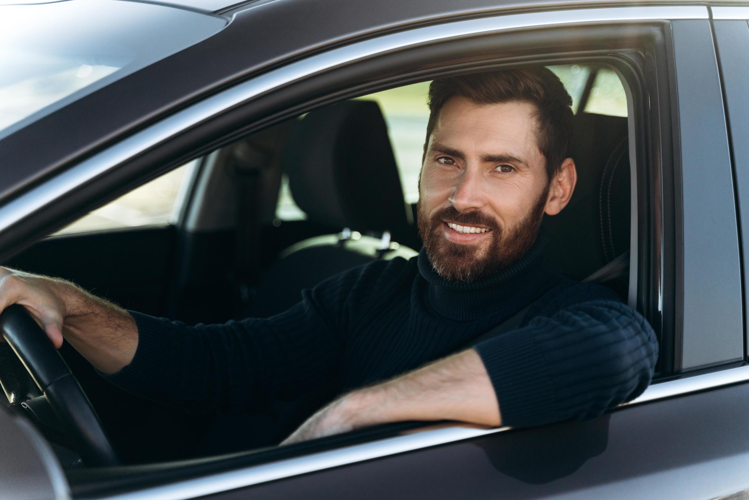 Happy caucasian man sitting and looking at the window while having long road by the car. Busy people and transportation concept Stock Free