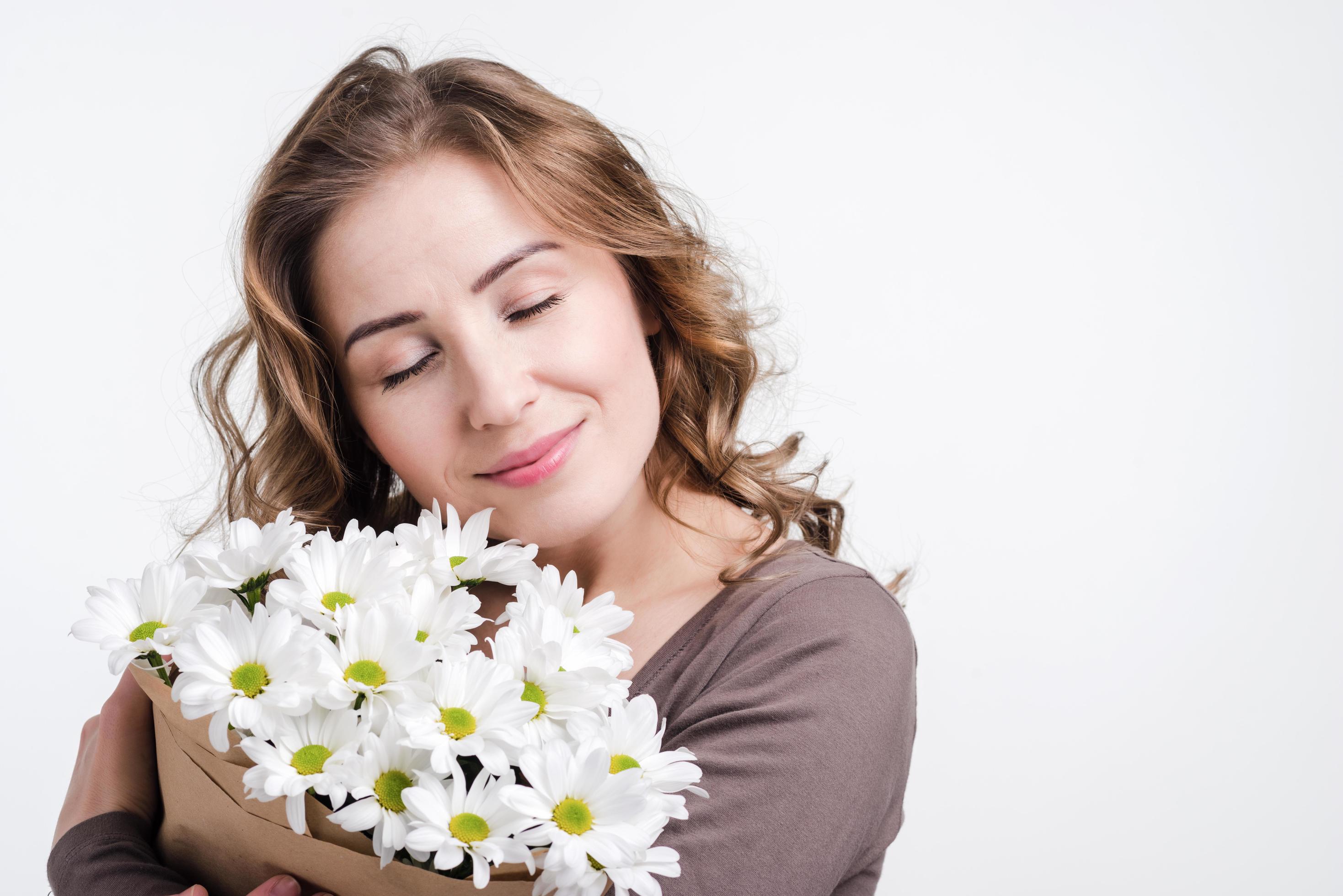 Girl holding flowers in studio on white wall background Stock Free