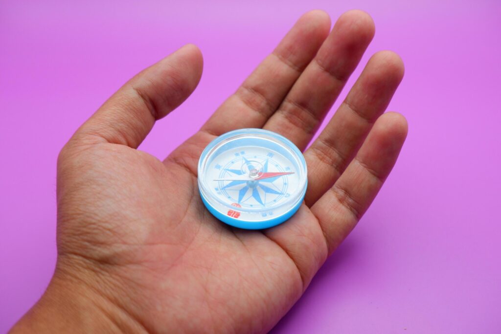 hand holding a compass isolated on a purple background Stock Free