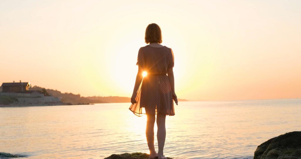 Young woman in dress relaxing on the summer beach during beautiful sunrise Stock Free