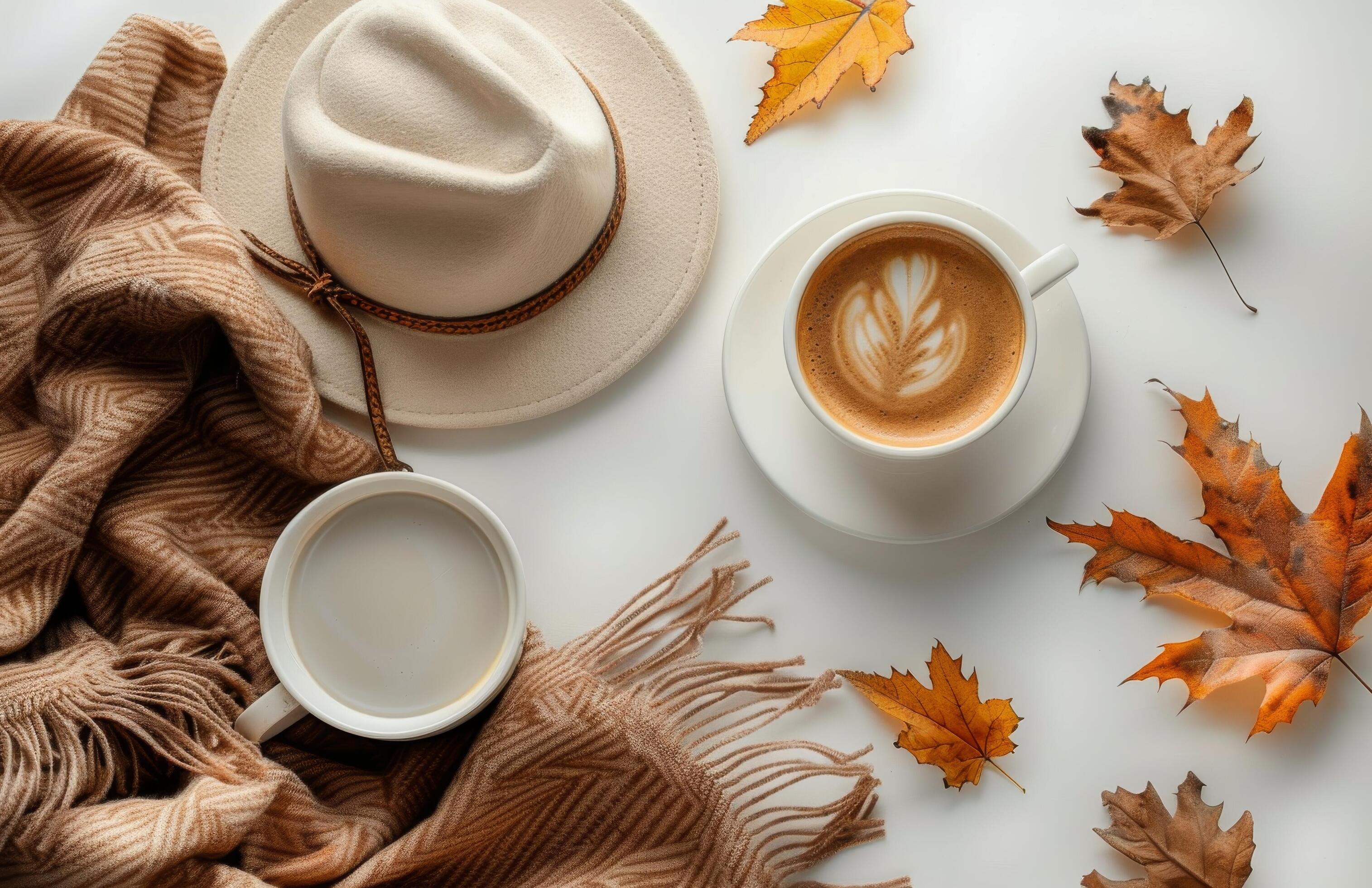 Autumnal Coffee Cup on White Table With Brown Scarf and Fall Leaves Stock Free