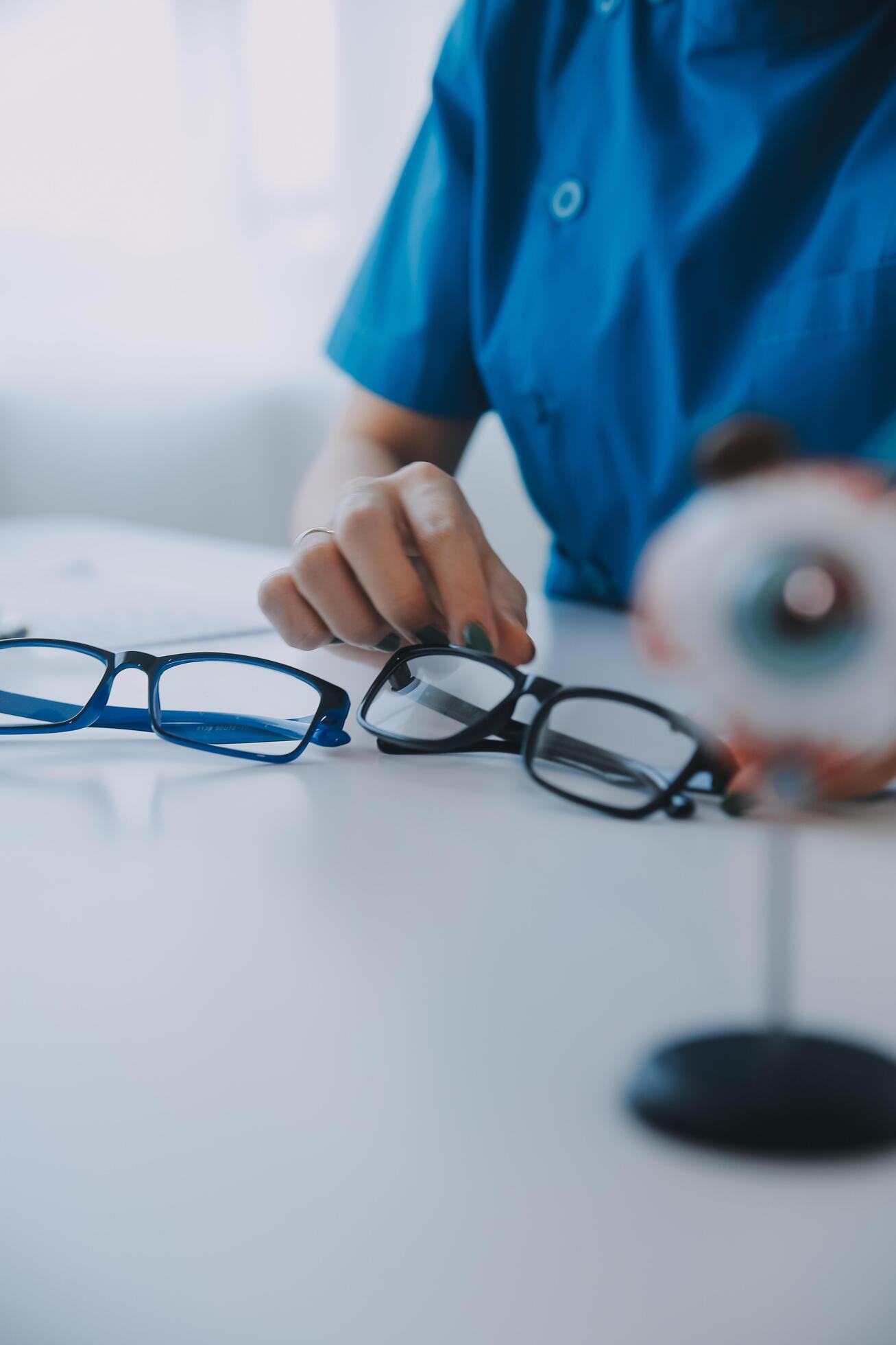 Close-up of Asian female doctor talking with elderly patient showing eyeball model and explaining eye disease in hospital Stock Free