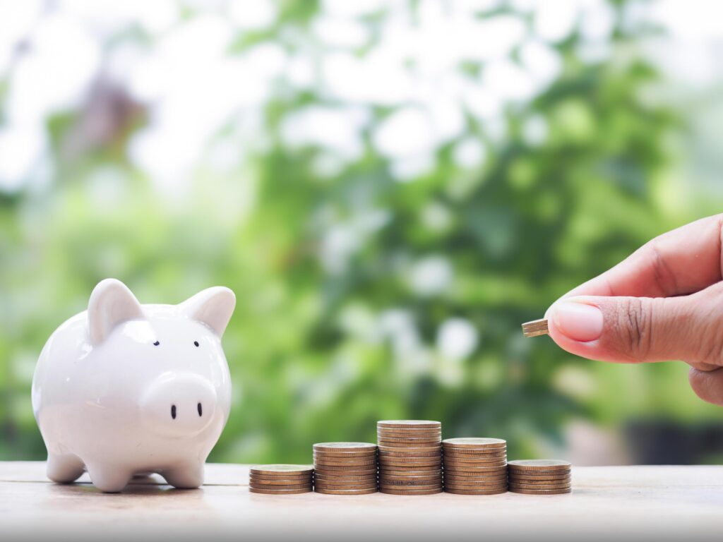 Close up of hand putting coins in stack of coins with piggy bank, The concept of saving money, Financial, Investment and Business growing. Stock Free