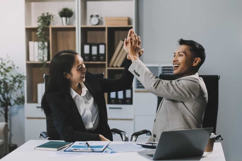 Young asian business woman giving high five with friends while working with computer laptop at office. Stock Free