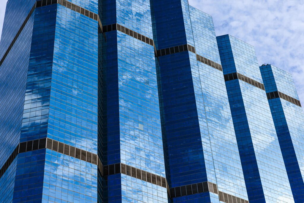 Blue sky and clouds reflected on the glass of office business buildings in the city center on a bright sunny day. Stock Free