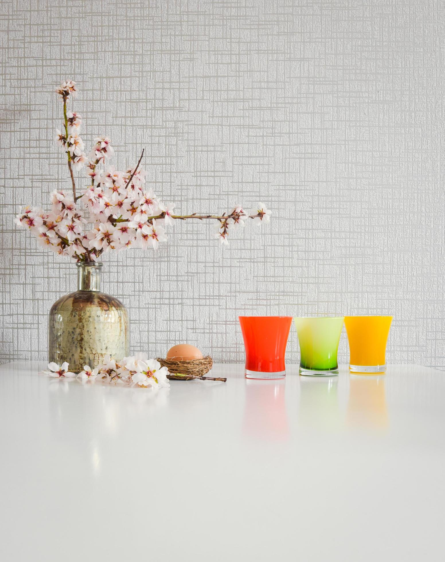 Bouquet style white kitchen table set up with yellow and green cups, blooming daisy flowers and an Easter egg Stock Free