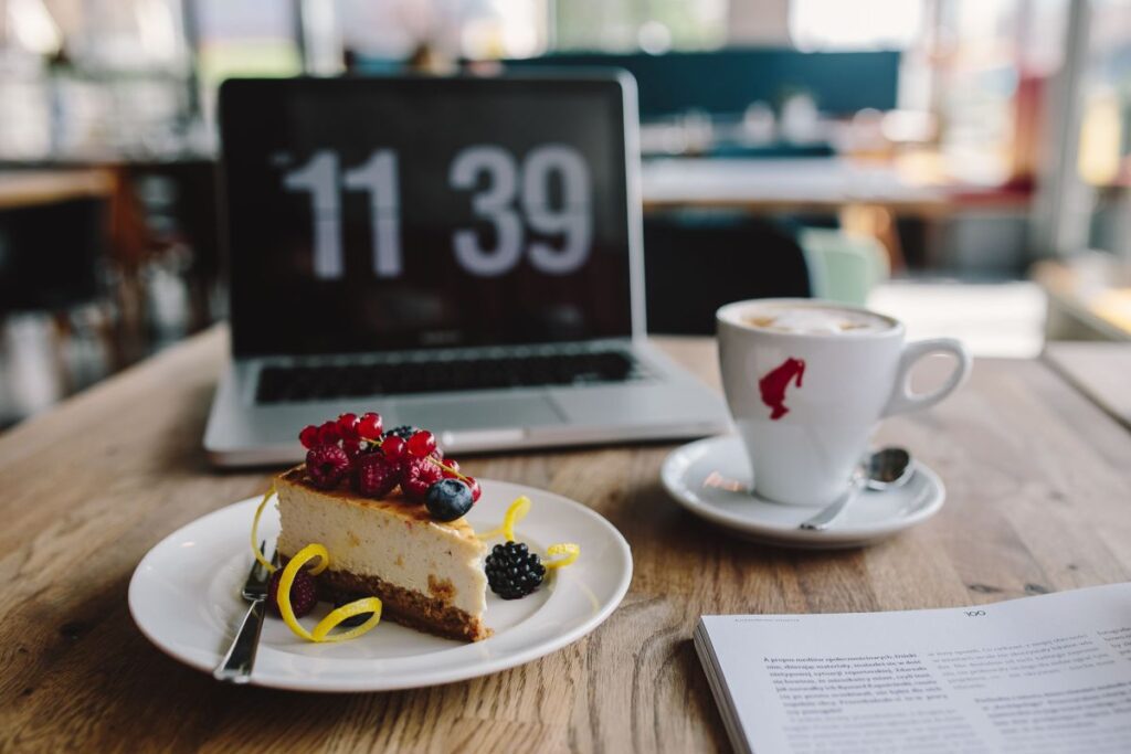 Working in a restaurant: Macbook, Cheese Cake and Cup of Coffee Stock Free