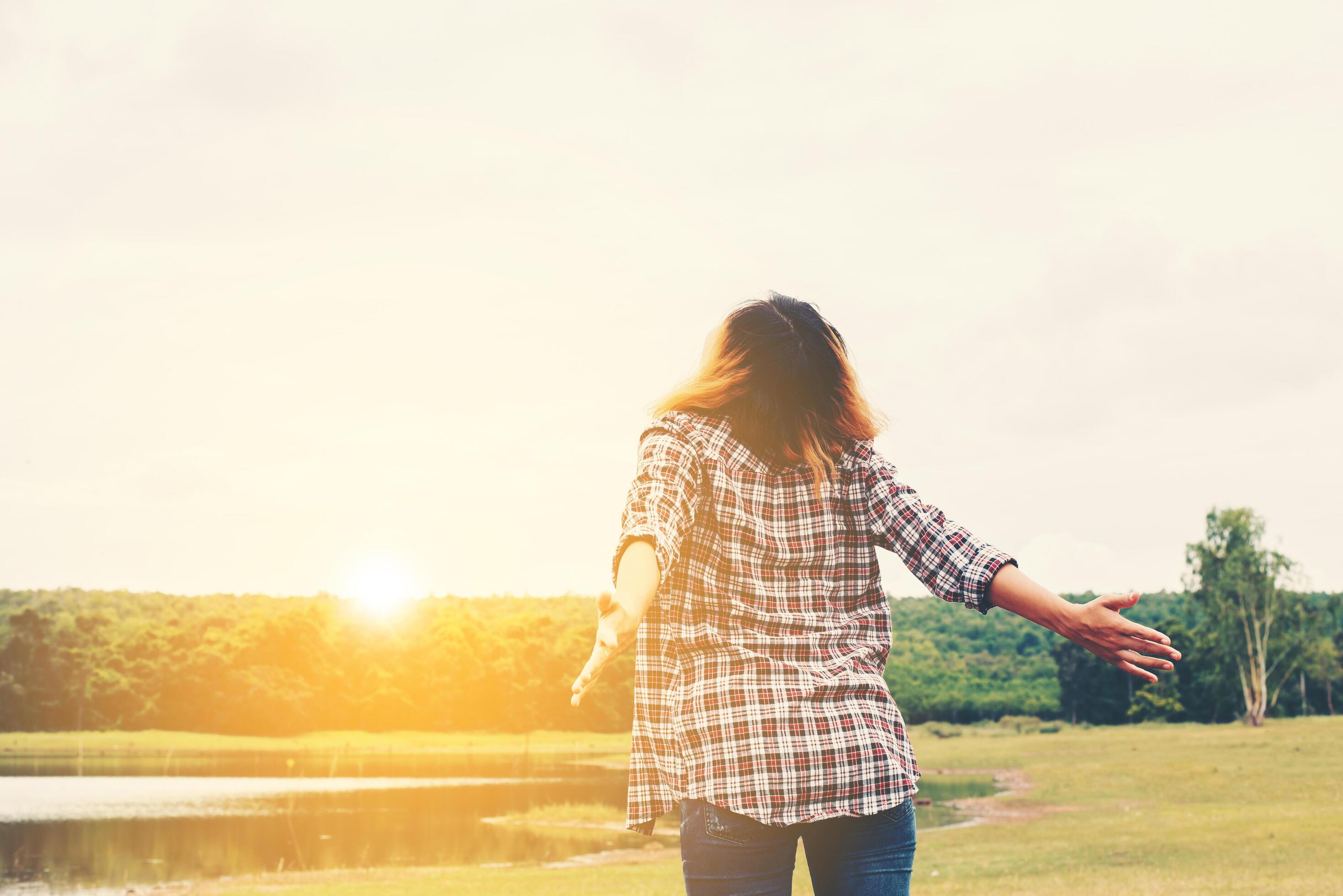 Woman lifestyle concept young beautiful woman stretching hands in the air enjoy with fresh air outside nature. Stock Free