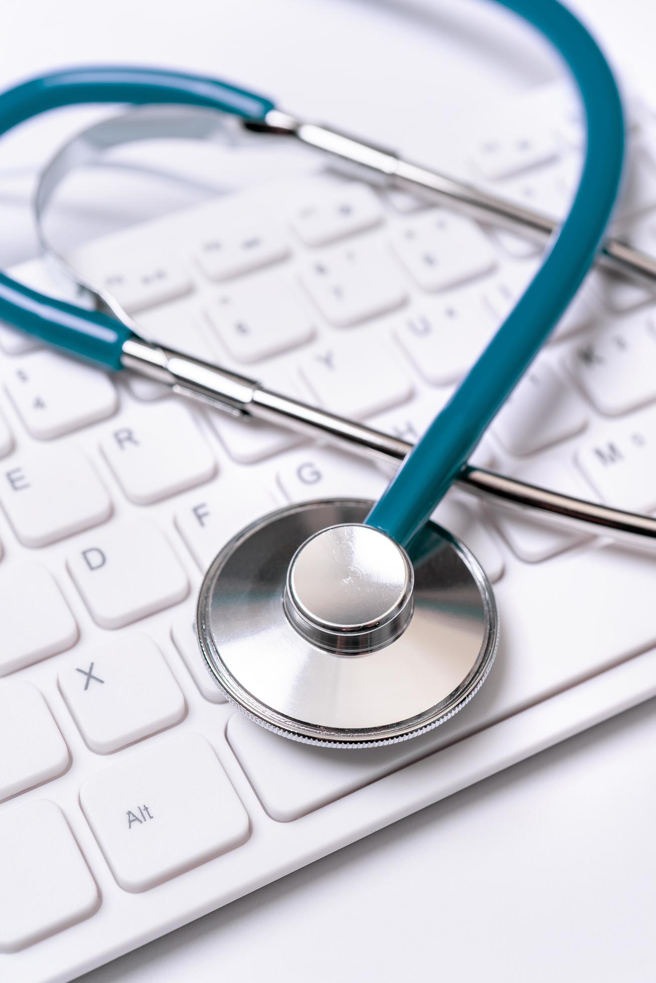 Stethoscope on computer keyboard on white background. Physician write medical case long term care treatment concept, close up, macro, copy space Stock Free