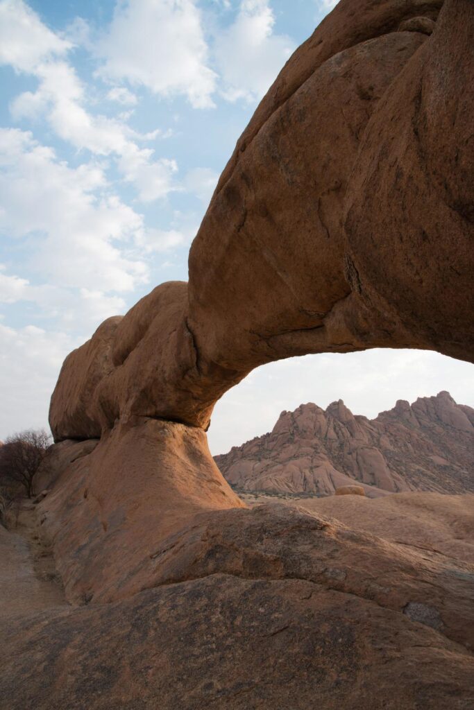 Beautiful natural arch in sandstone. Mountains in the distance. Damaraland, Namibia Stock Free