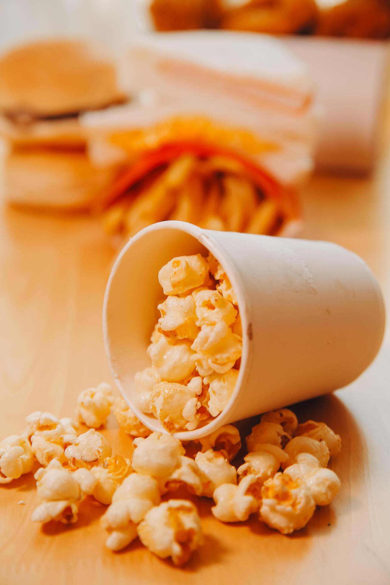 A bucket of popcorn, top-view, warm colors, light brown wooden background, flat lay, daylight macro close-up Stock Free