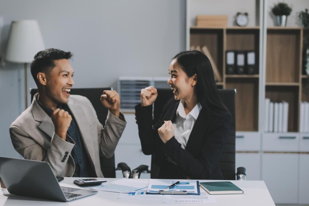 Young asian business woman giving high five with friends while working with computer laptop at office. Stock Free