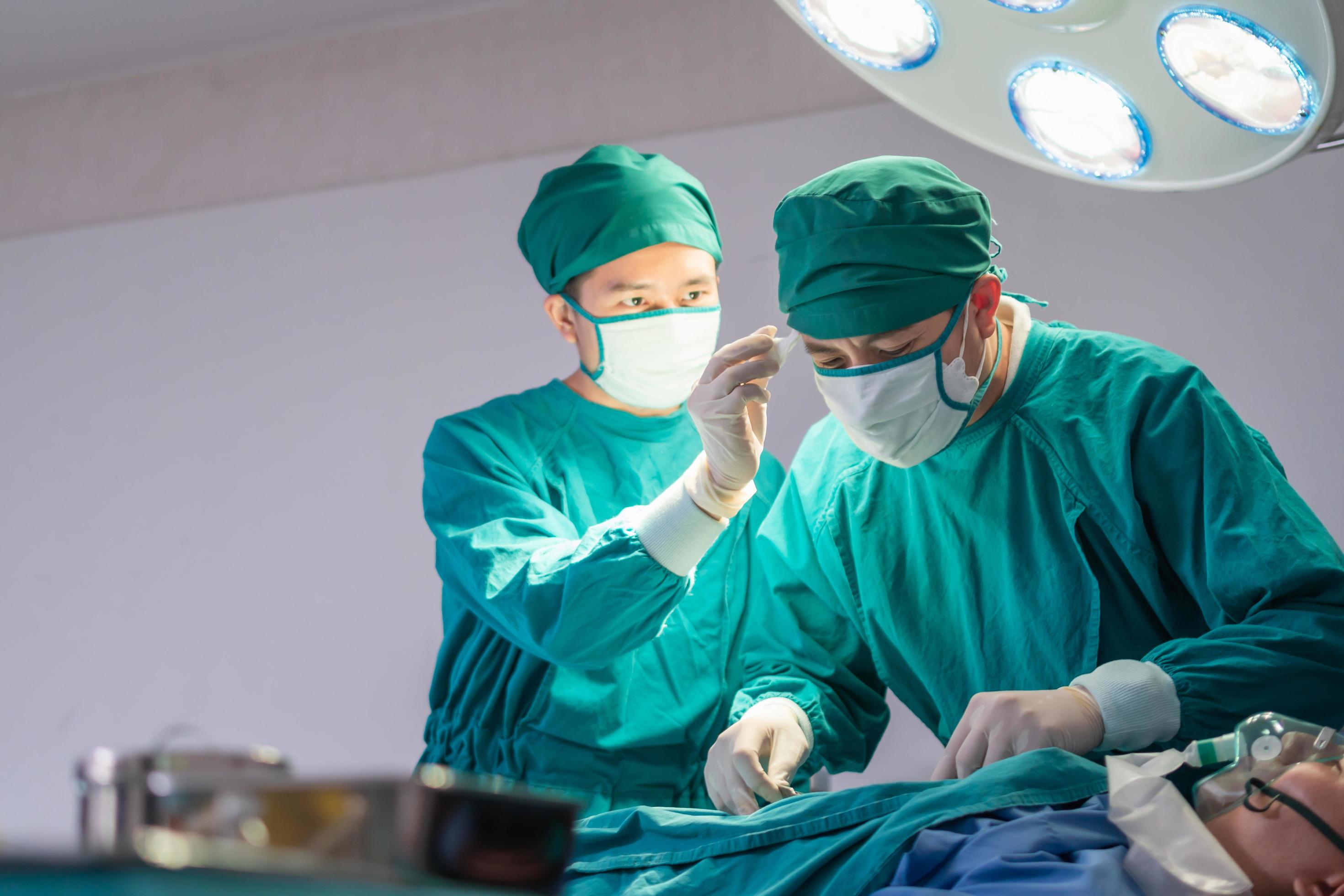 Medical team performing surgical operation in operating Room, Concentrated surgical team operating a patient Stock Free