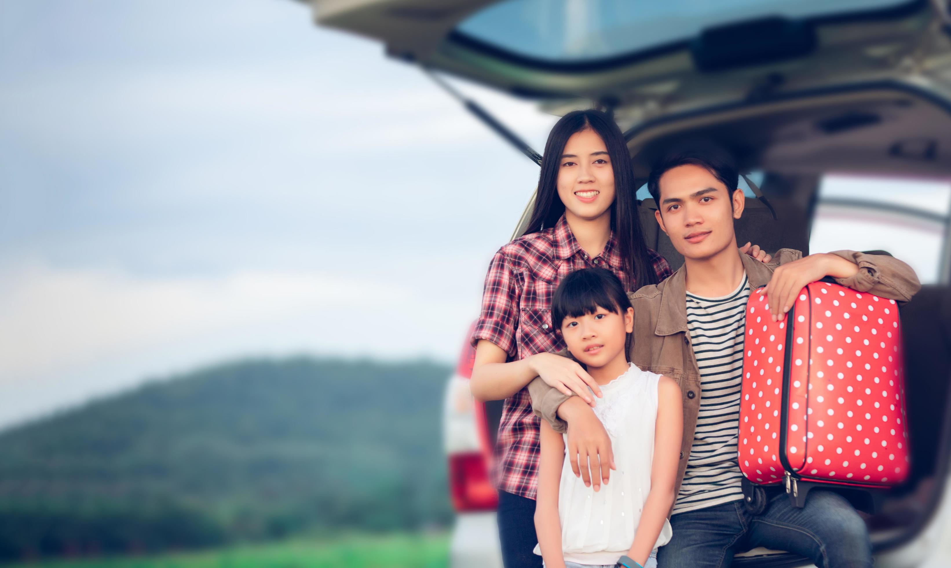 Happy little girl with asian family sitting in the car for enjoying road trip and summer vacation in camper van Stock Free