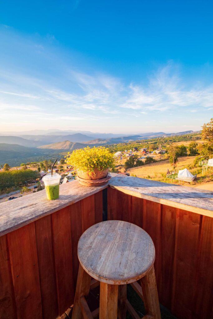 A view of the hill from the coffee shop, including a sunset in the background and a wooden chair placed into a corner. Stock Free