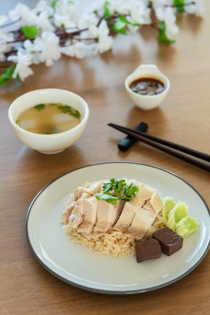 Traditional Singapore chicken rice with salted soybeans sauce and soup on wooden background Stock Free