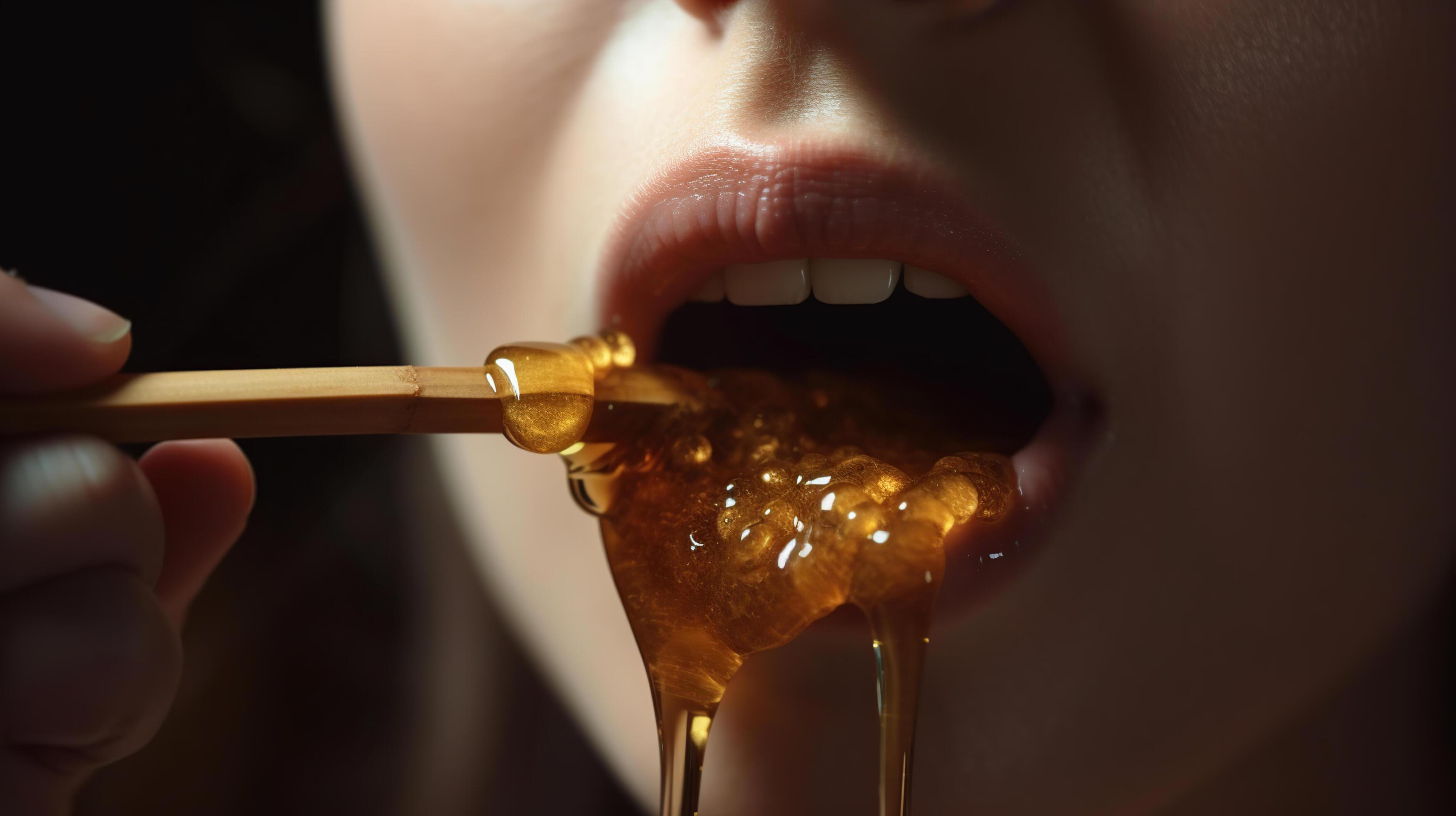 Honey dripping from honey dipper on girl lips. Beauty model woman open mouth, model eating nectar. Healthy food concept, diet, dessert, Stock Free