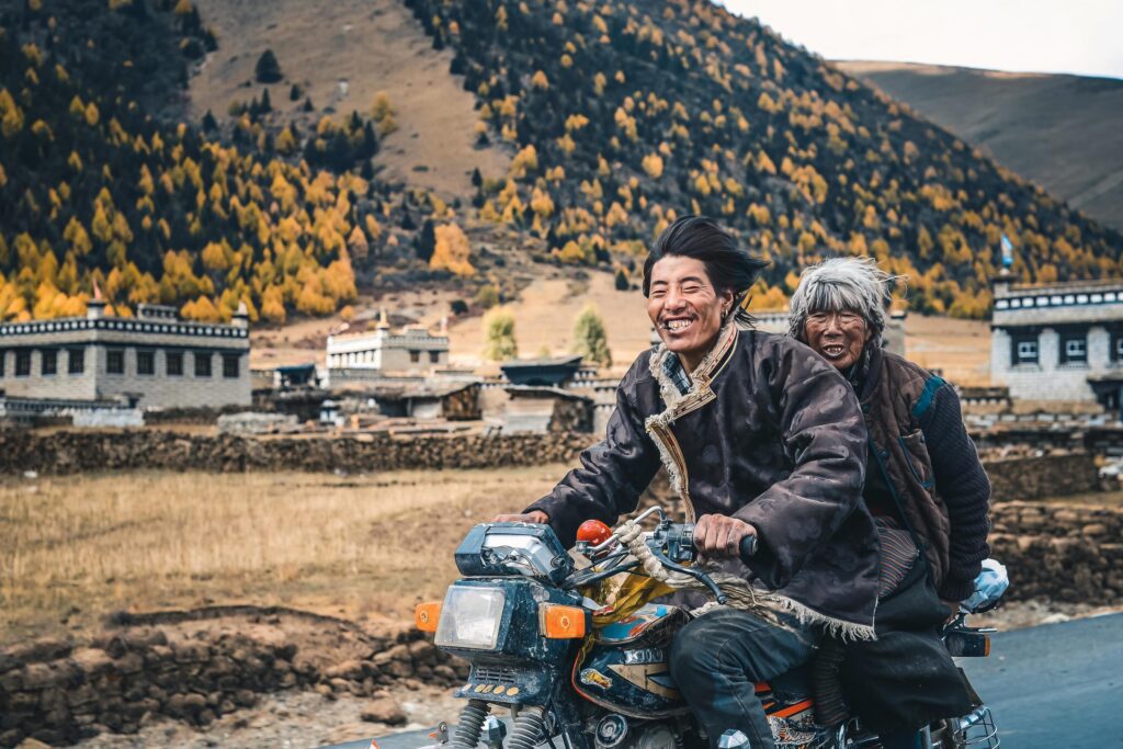 Happy Tibetan people riding motorcycles in high mountains Stock Free