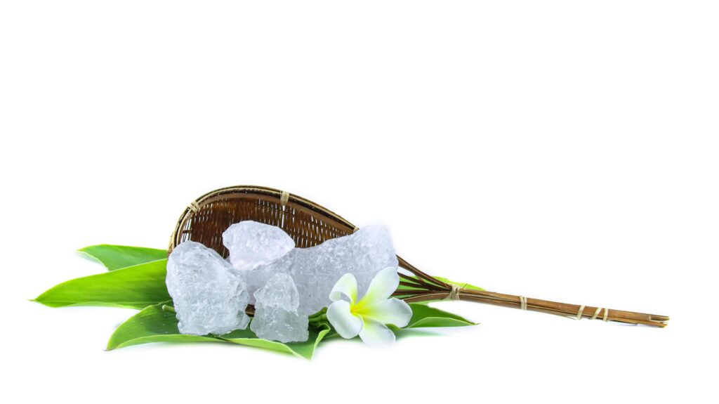 White crystal clear alum cube on green leaf isolated on white background. Stock Free