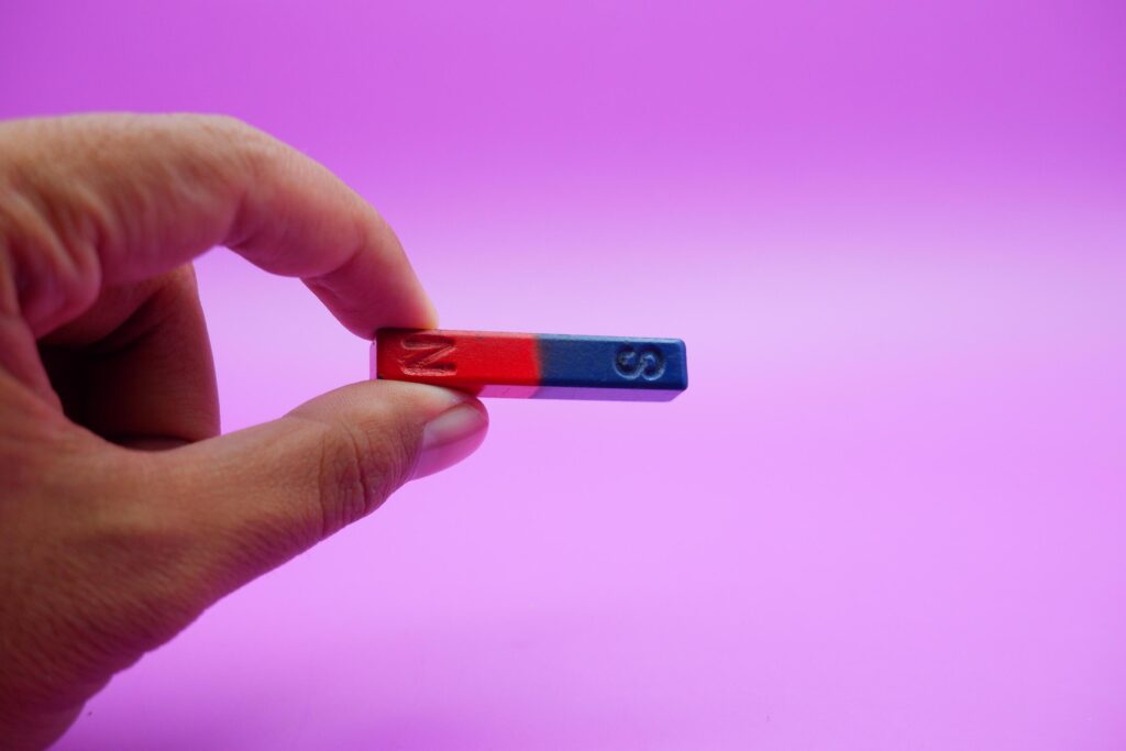 hand holding a bar magnet isolated on a purple background Stock Free