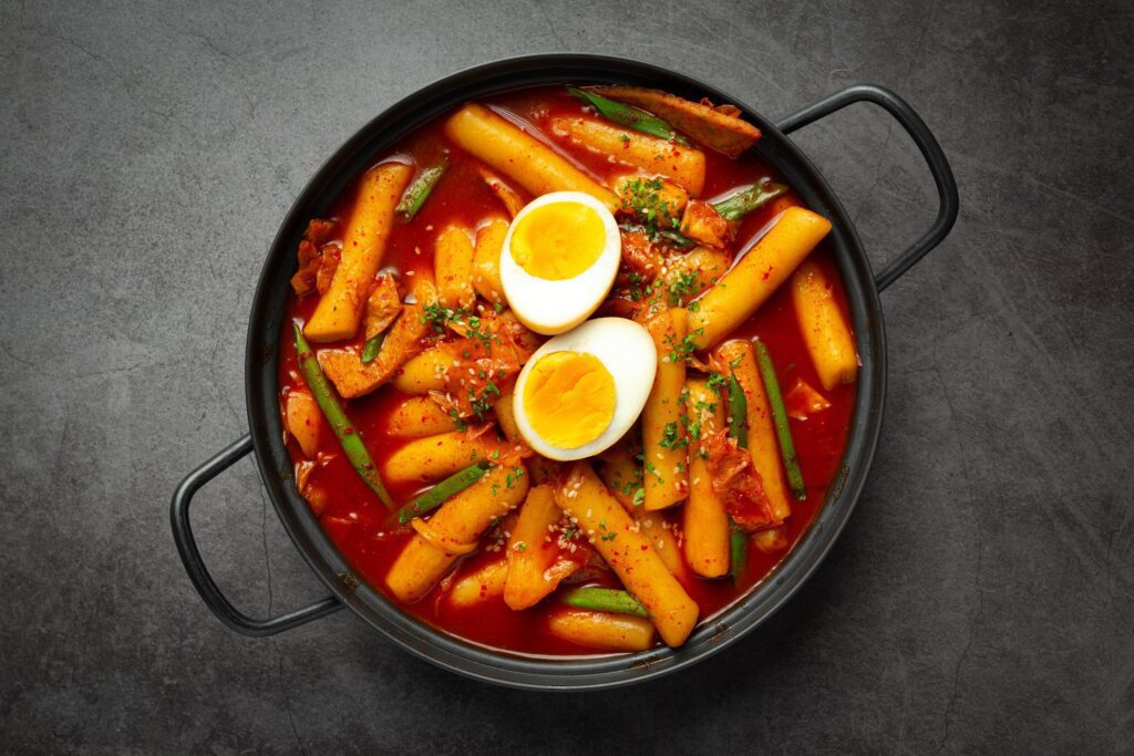 Cheesy Tokbokki korean traditional food on black board background. Lunch dish. Stock Free