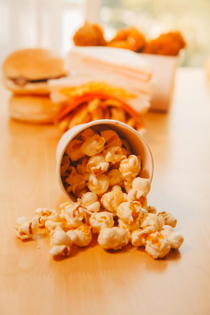 A bucket of popcorn, top-view, warm colors, light brown wooden background, flat lay, daylight macro close-up Stock Free