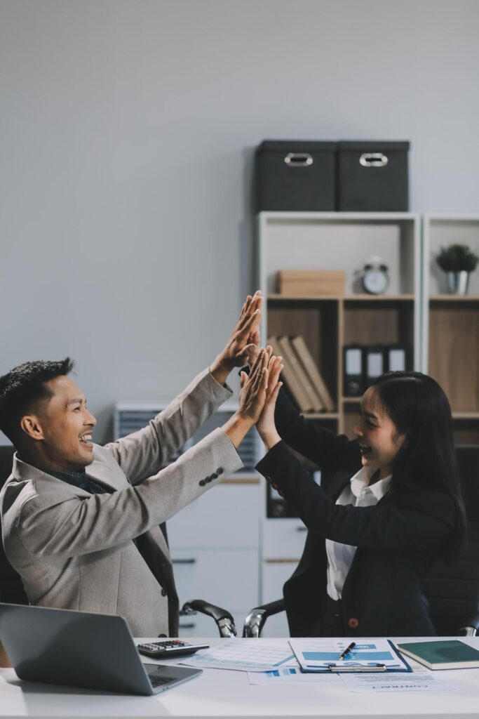 Young asian business woman giving high five with friends while working with computer laptop at office. Stock Free