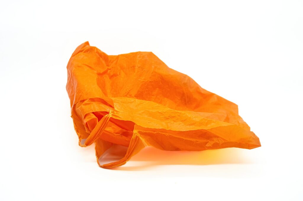 orange plastic bag crumpled on white background. Copy space Stock Free