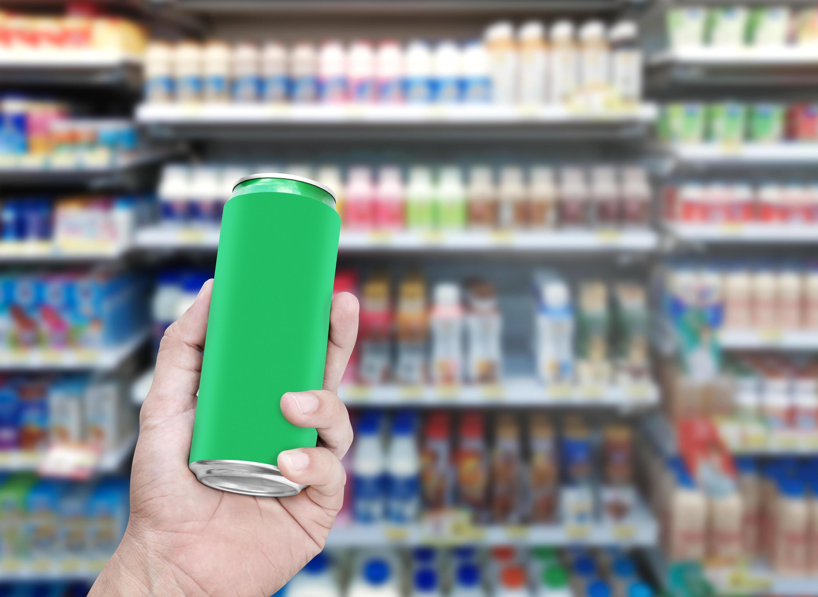 Hand hold mockup green aluminum can with many drinks on shelf background Stock Free