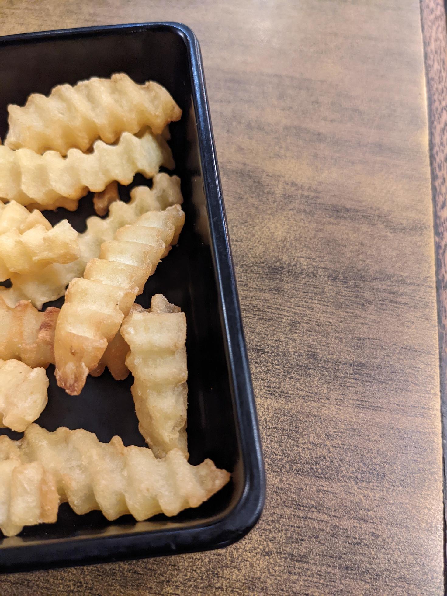 Close up fried fries with wooden table on the restaurant. The photo is suitable to use for traditional food background, poster and food content. Stock Free